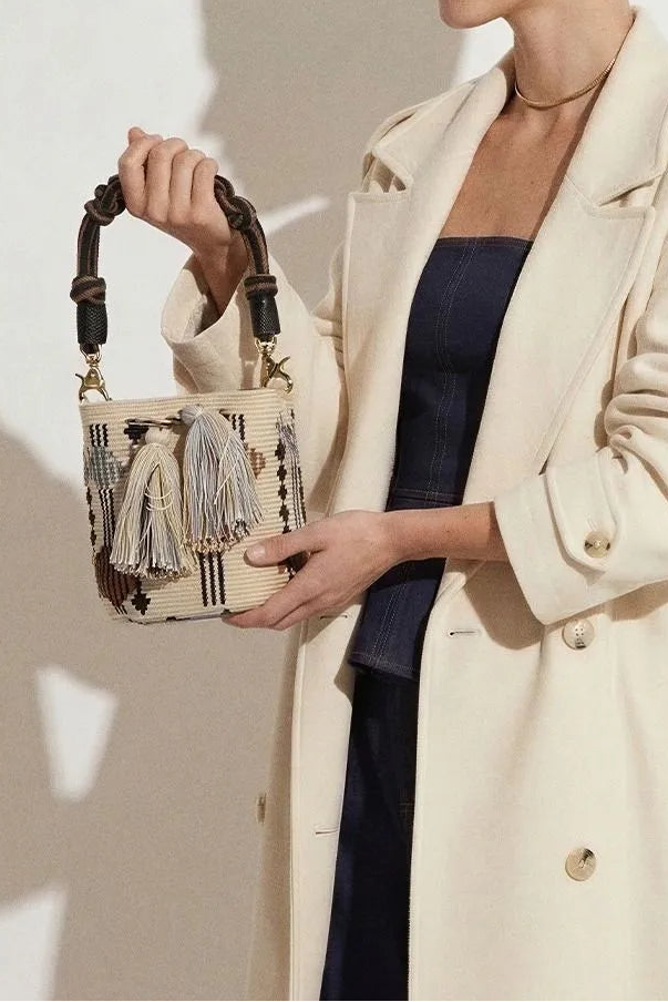 Woman holding a decorative handbag against a plain background