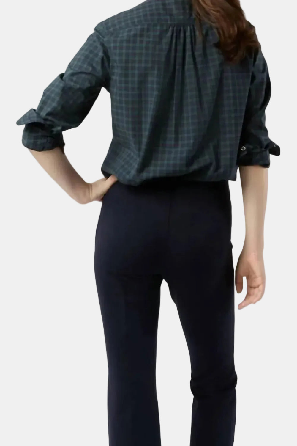 Person wearing a green plaid shirt and black pants on a white background