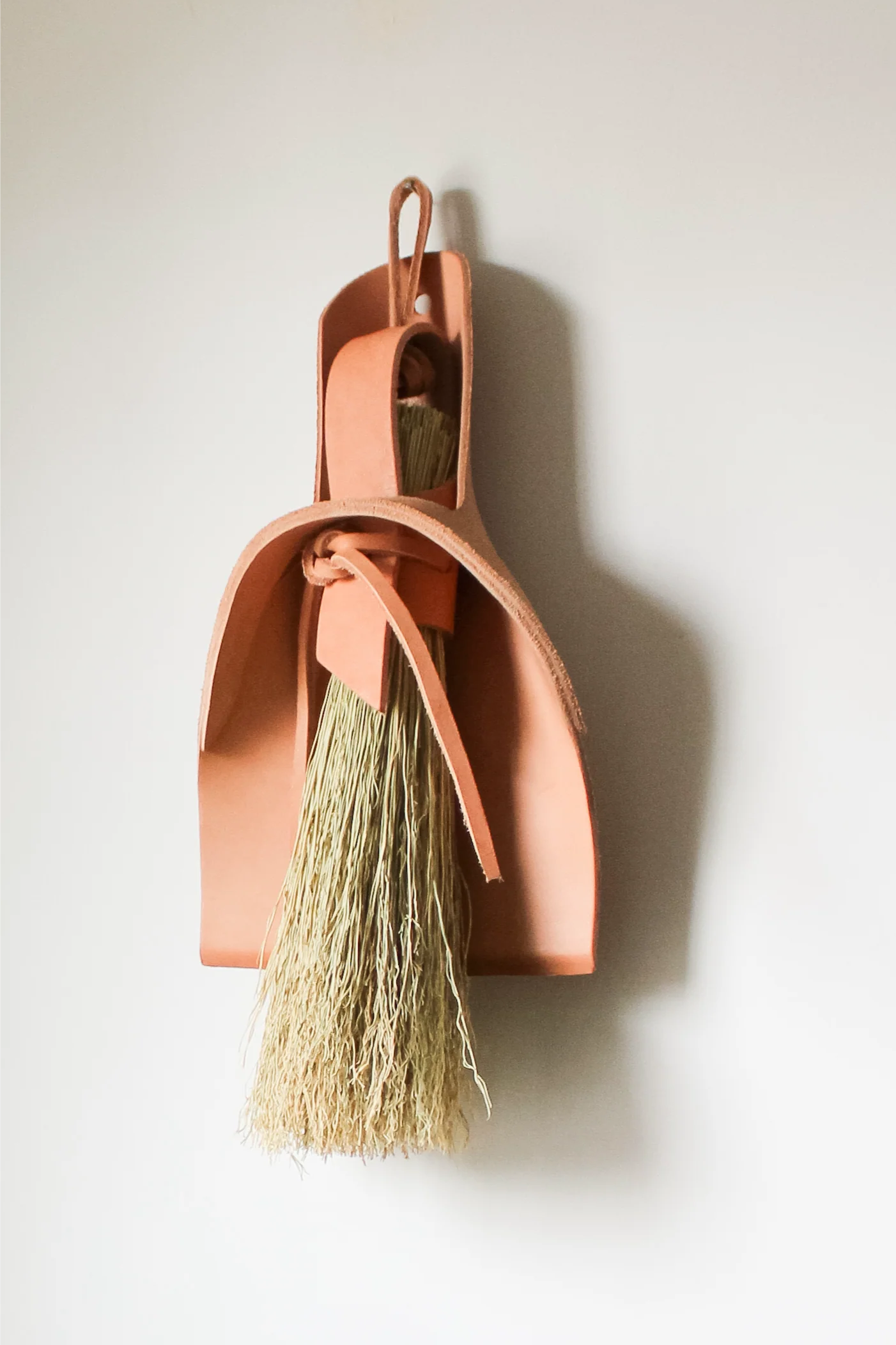 Copper broom and dustpan set against a plain background