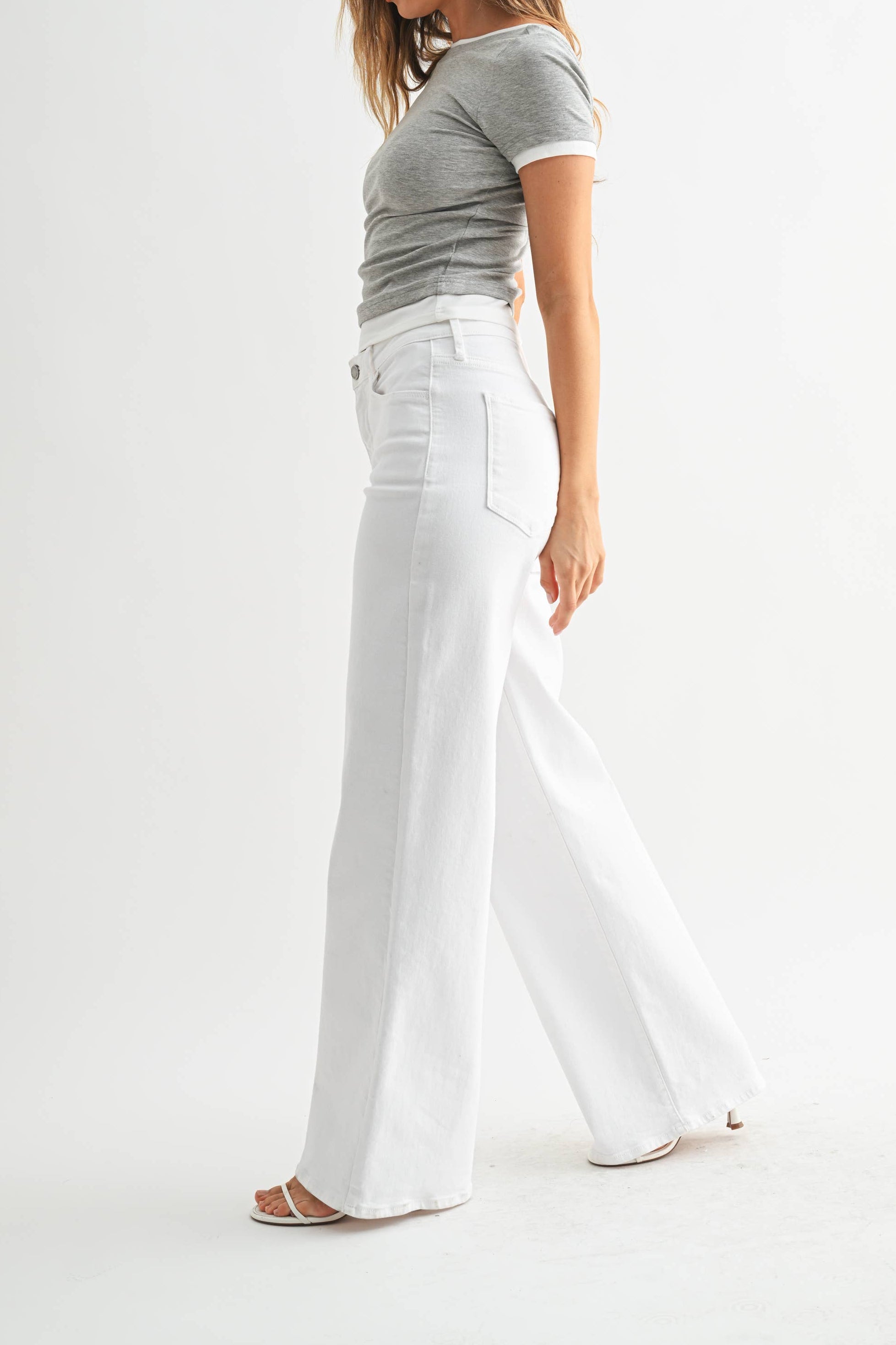 Woman wearing a gray t-shirt and white pants on a white background
