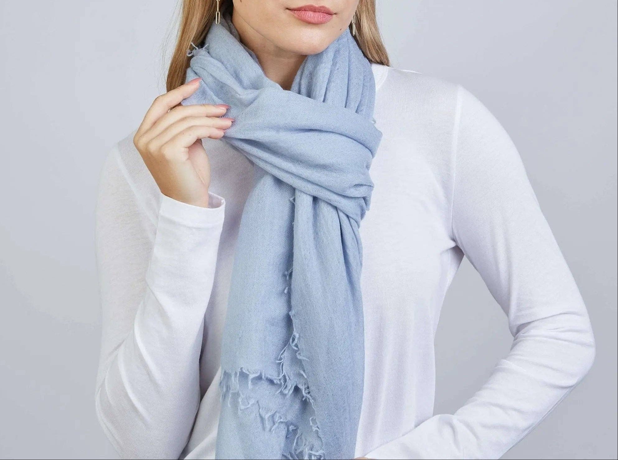 Woman wearing a light blue scarf against a plain background