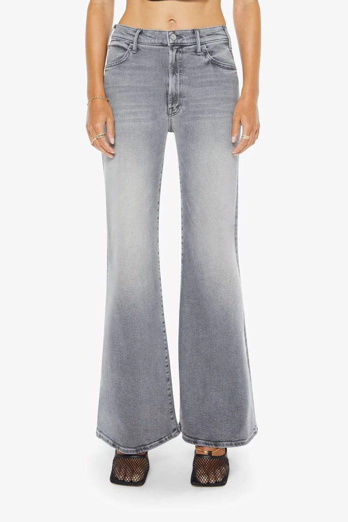 Woman wearing a black tank top and gray flared jeans on a white background