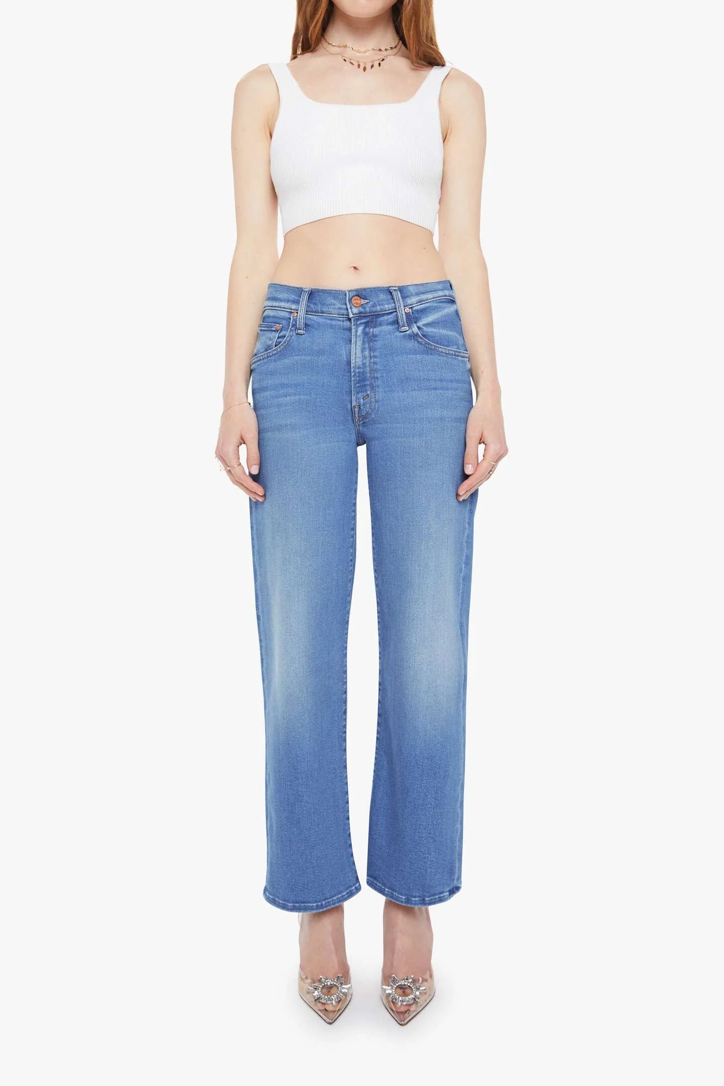 Woman wearing a white crop top and blue jeans on a white background