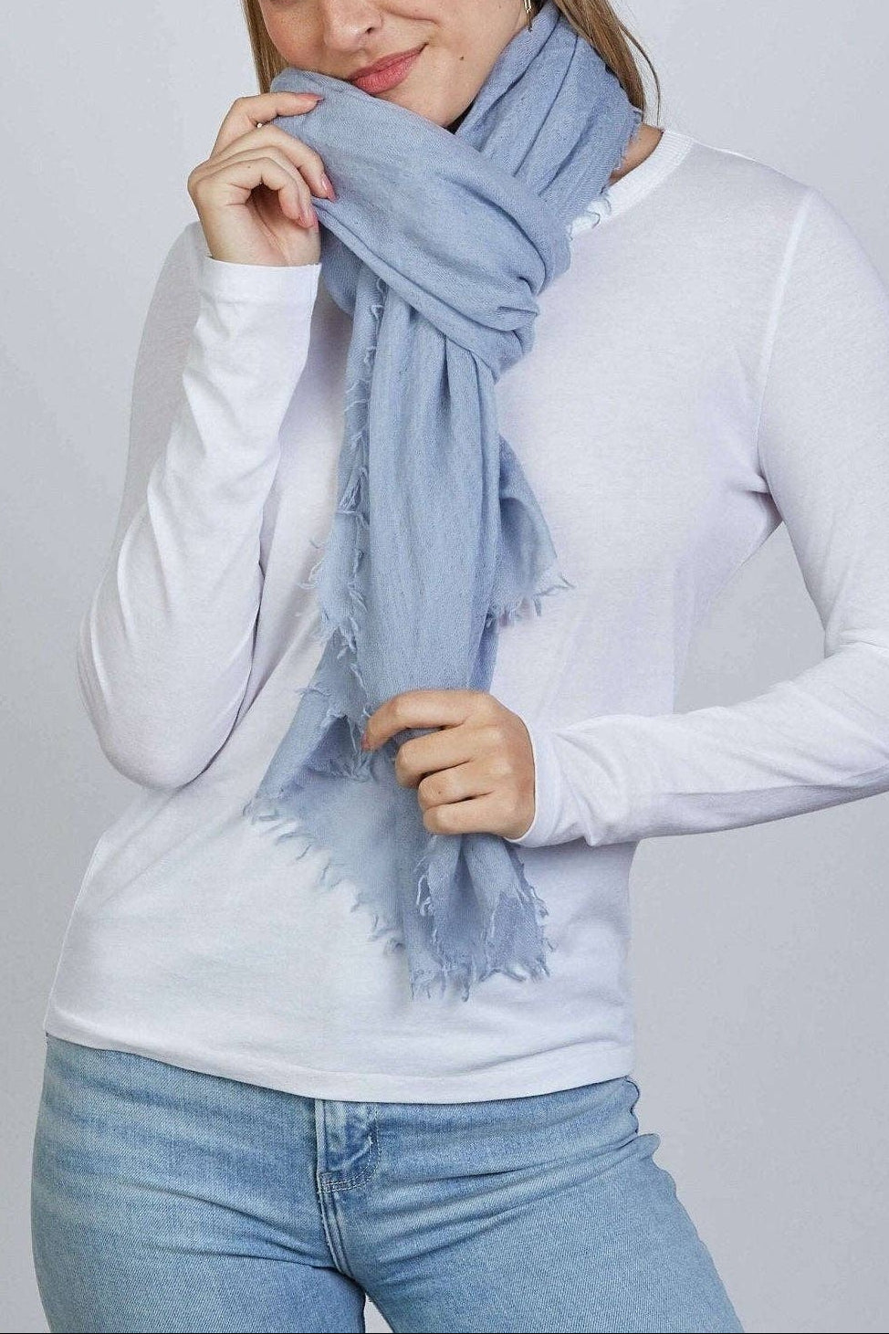 Woman wearing a light blue scarf against a plain background