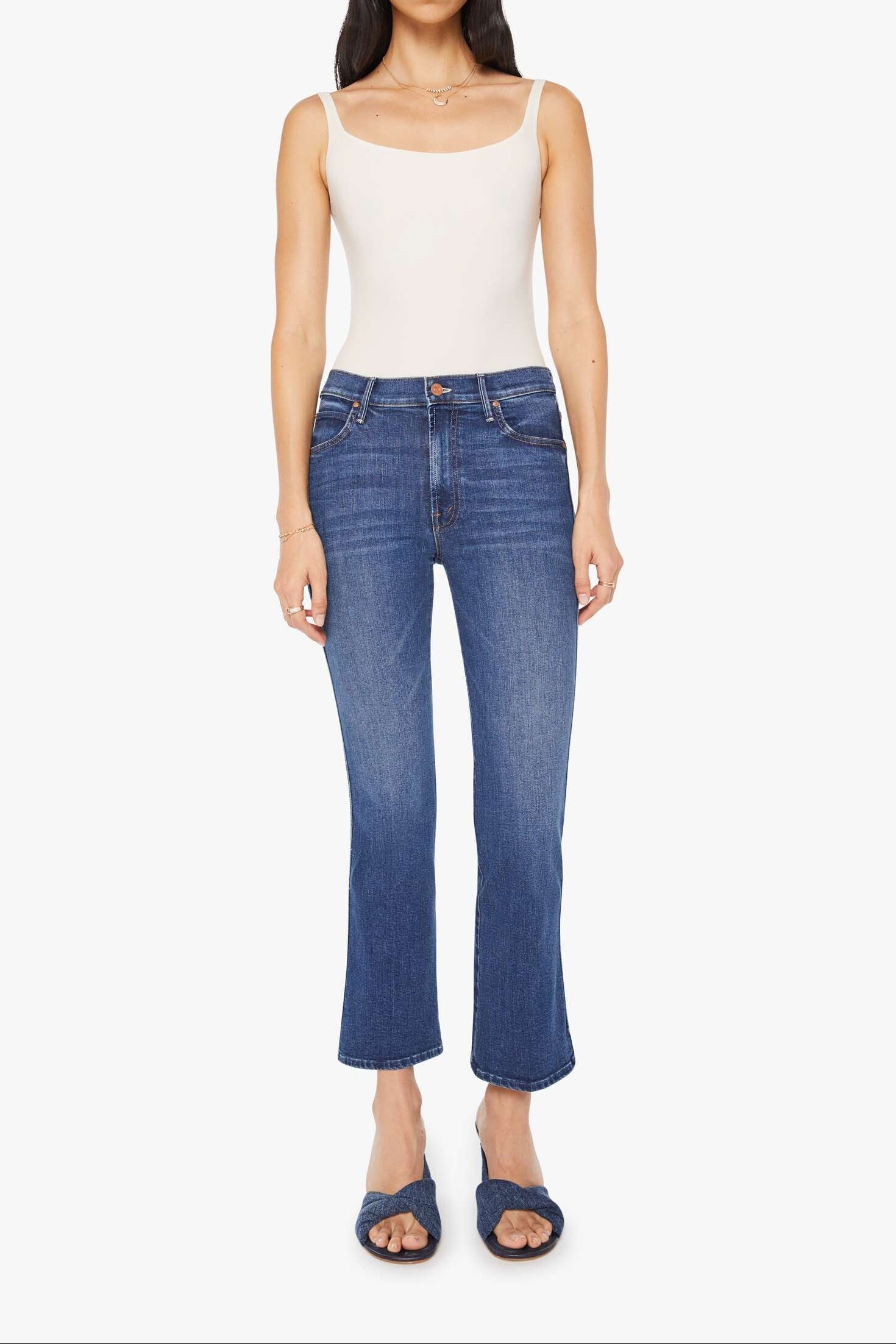 Woman wearing blue jeans and a white top on a white background
