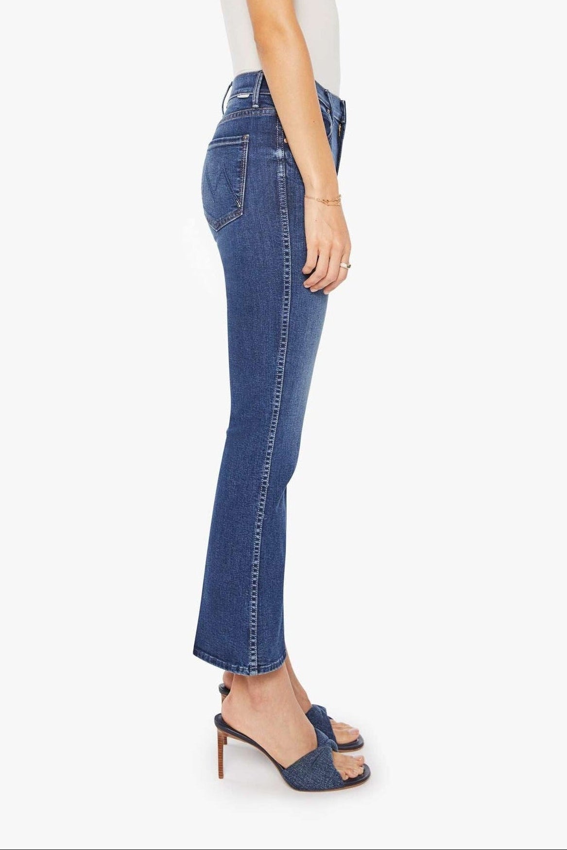 Woman wearing blue jeans and a white top on a white background