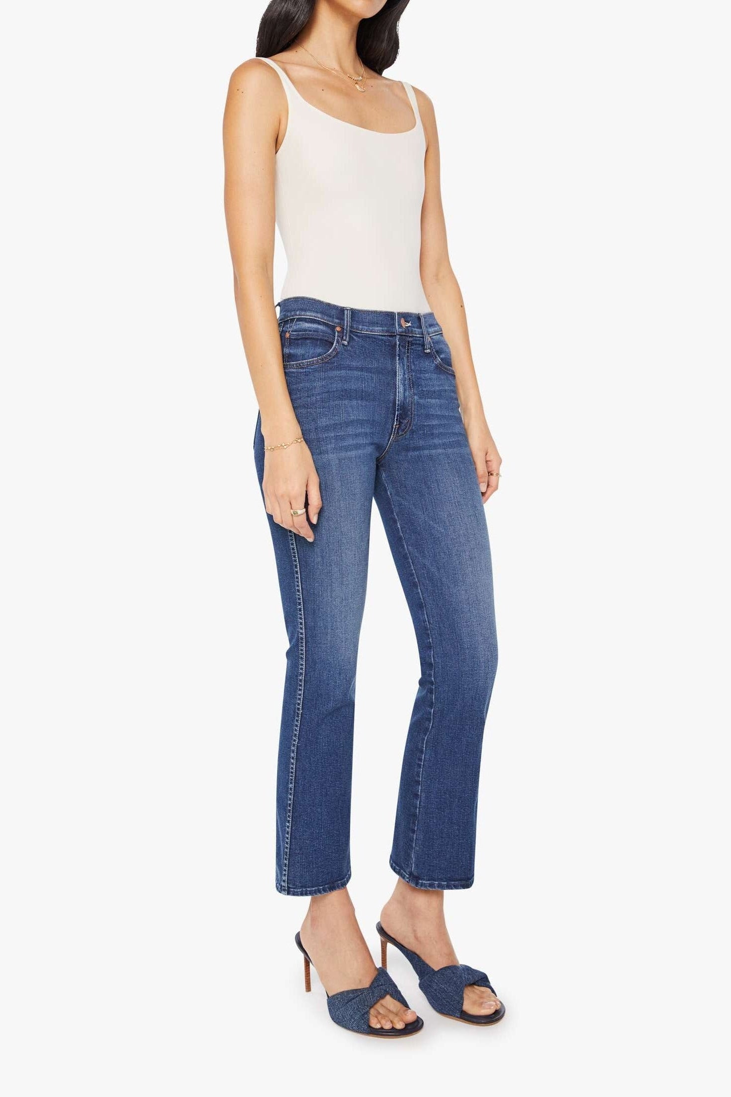 Woman wearing blue jeans and a white top on a white background