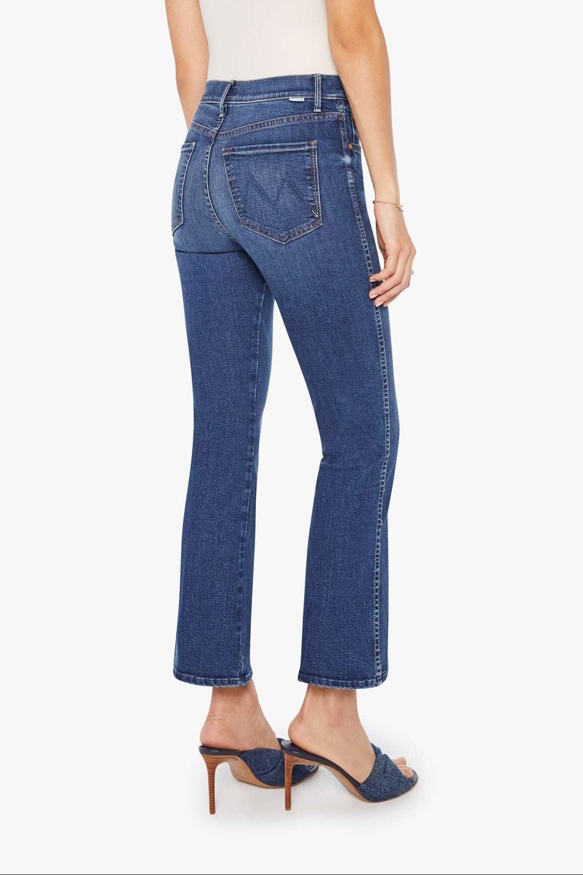 Woman wearing blue jeans and a white top on a white background