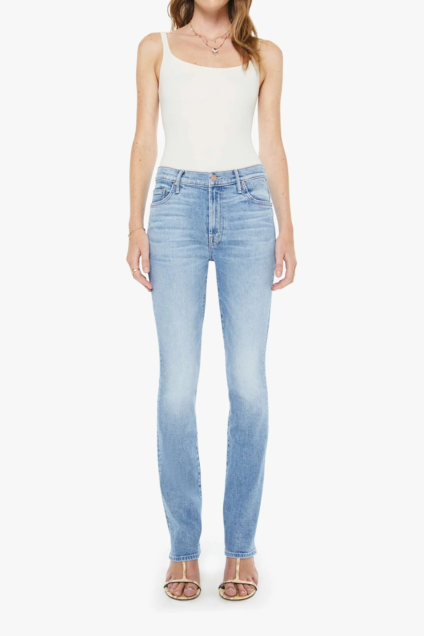Woman wearing light blue jeans and a white top on a white background