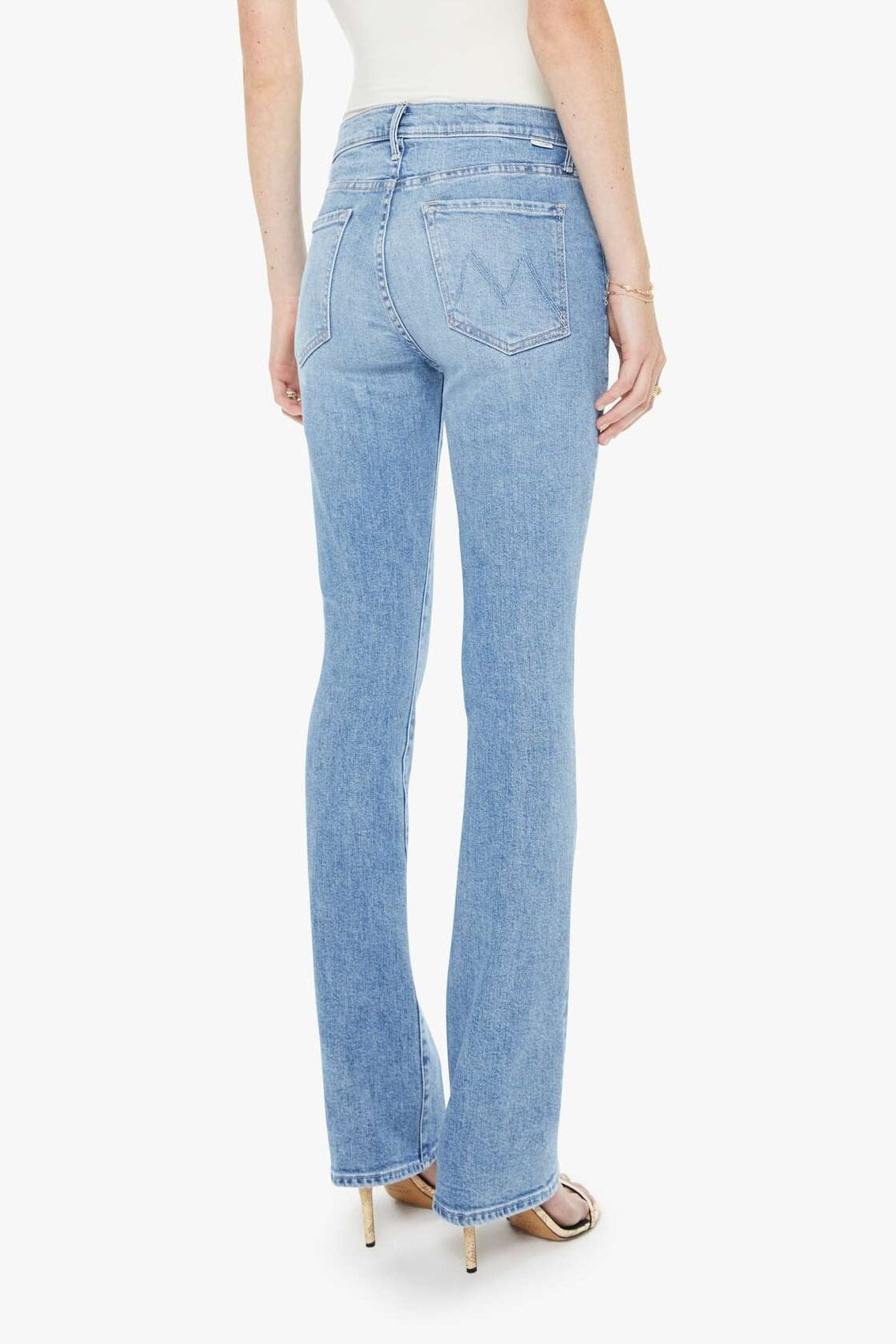 Woman wearing light blue jeans and a white top on a white background