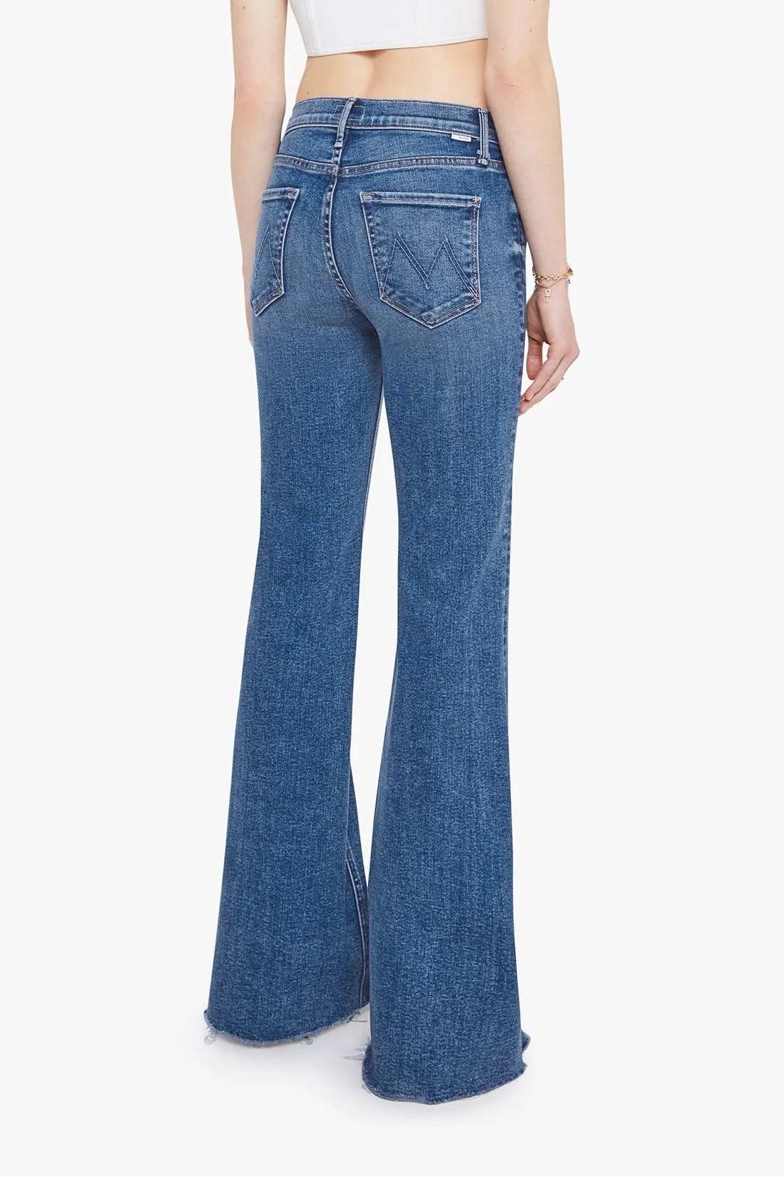A model shown from the back wearing blue high-waisted flare jeans and a white crop top against a plain white background.