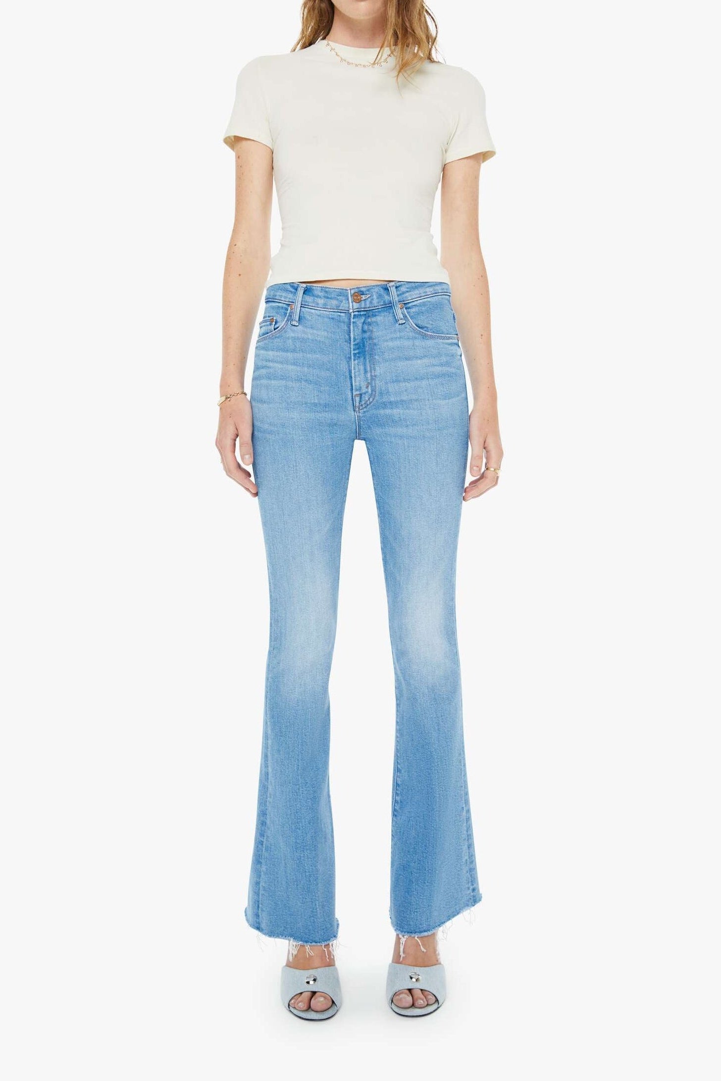 Woman wearing light blue jeans and a white top on a white background