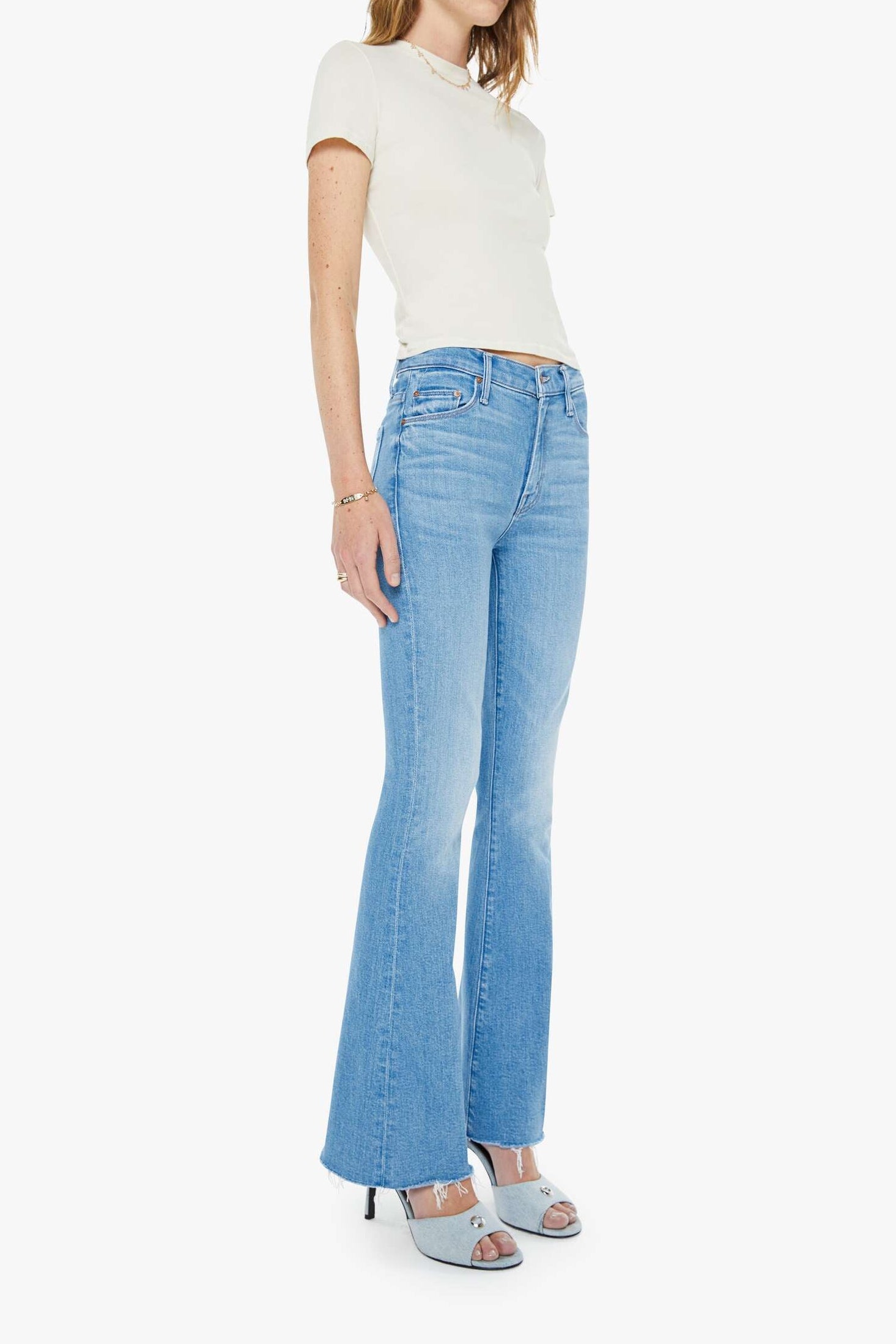 Woman wearing a white top and light blue jeans on a white background