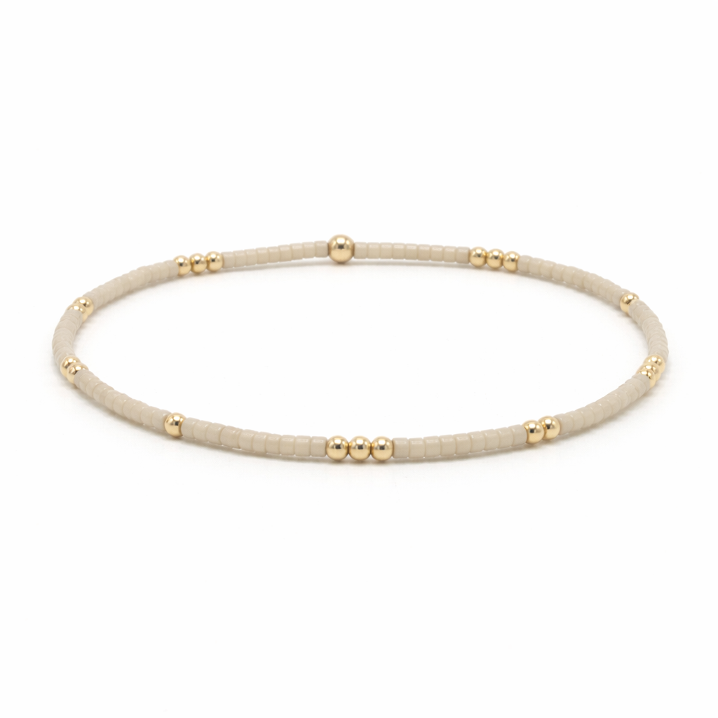 Beige beaded necklace with gold accents on a white background