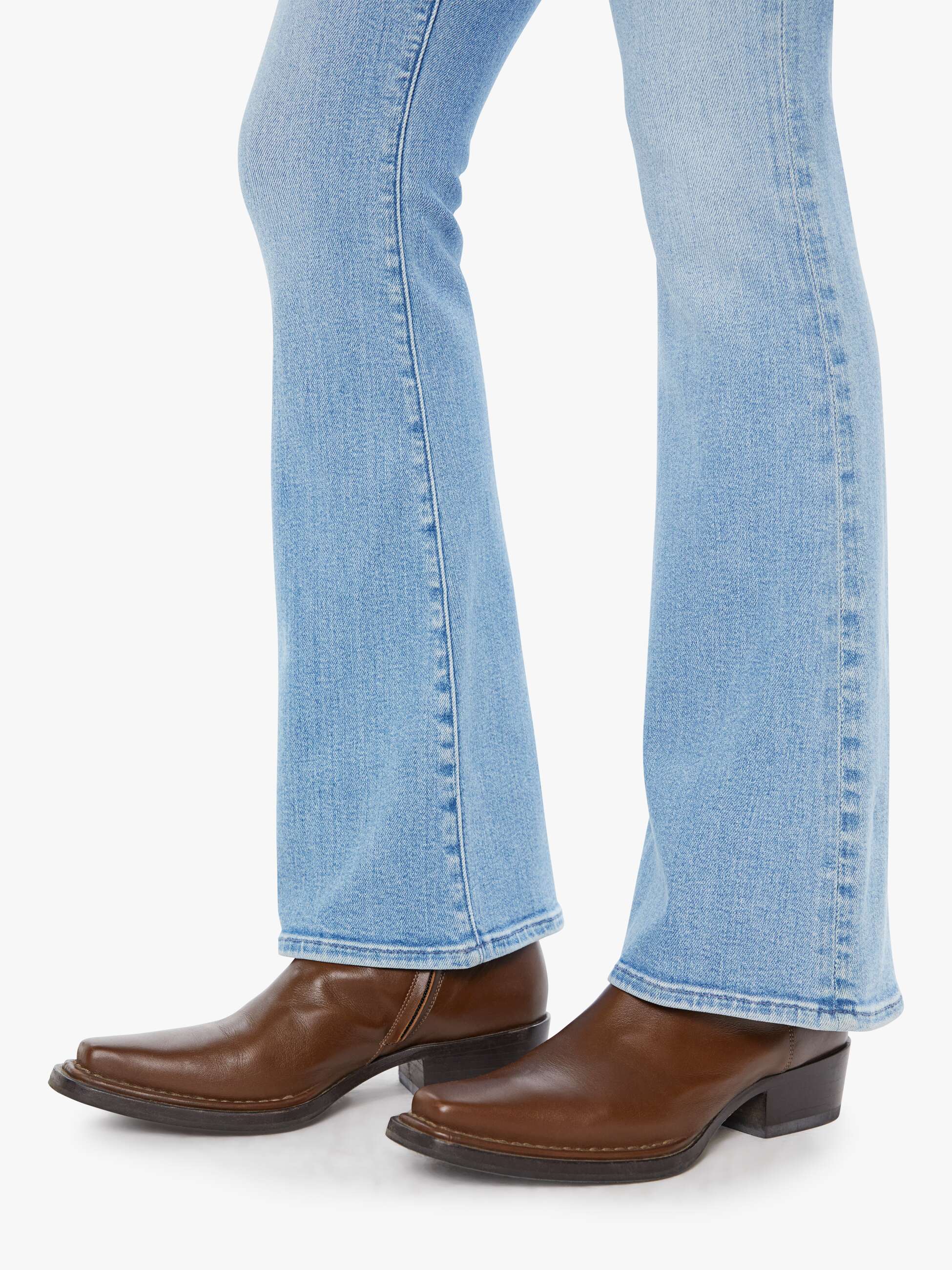 Brown leather boots worn with light blue jeans on a white background