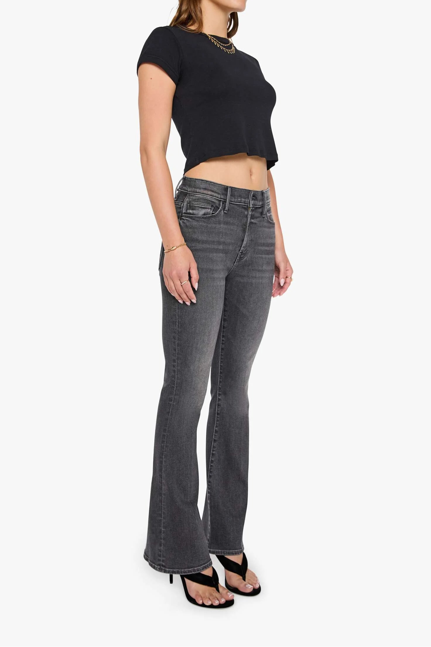 Woman wearing black top and gray flared jeans on a white background