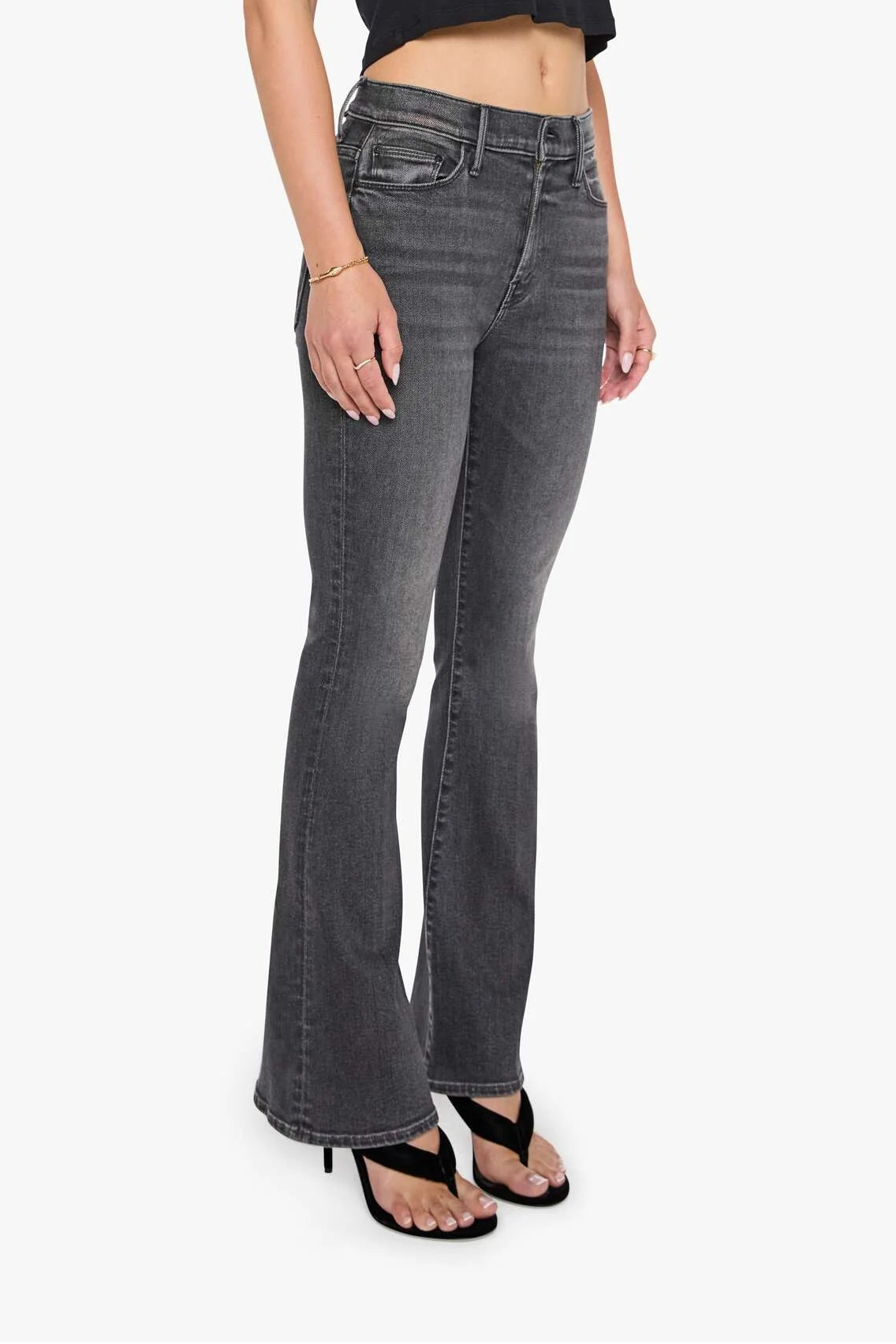 Woman wearing black top and gray flared jeans on a white background