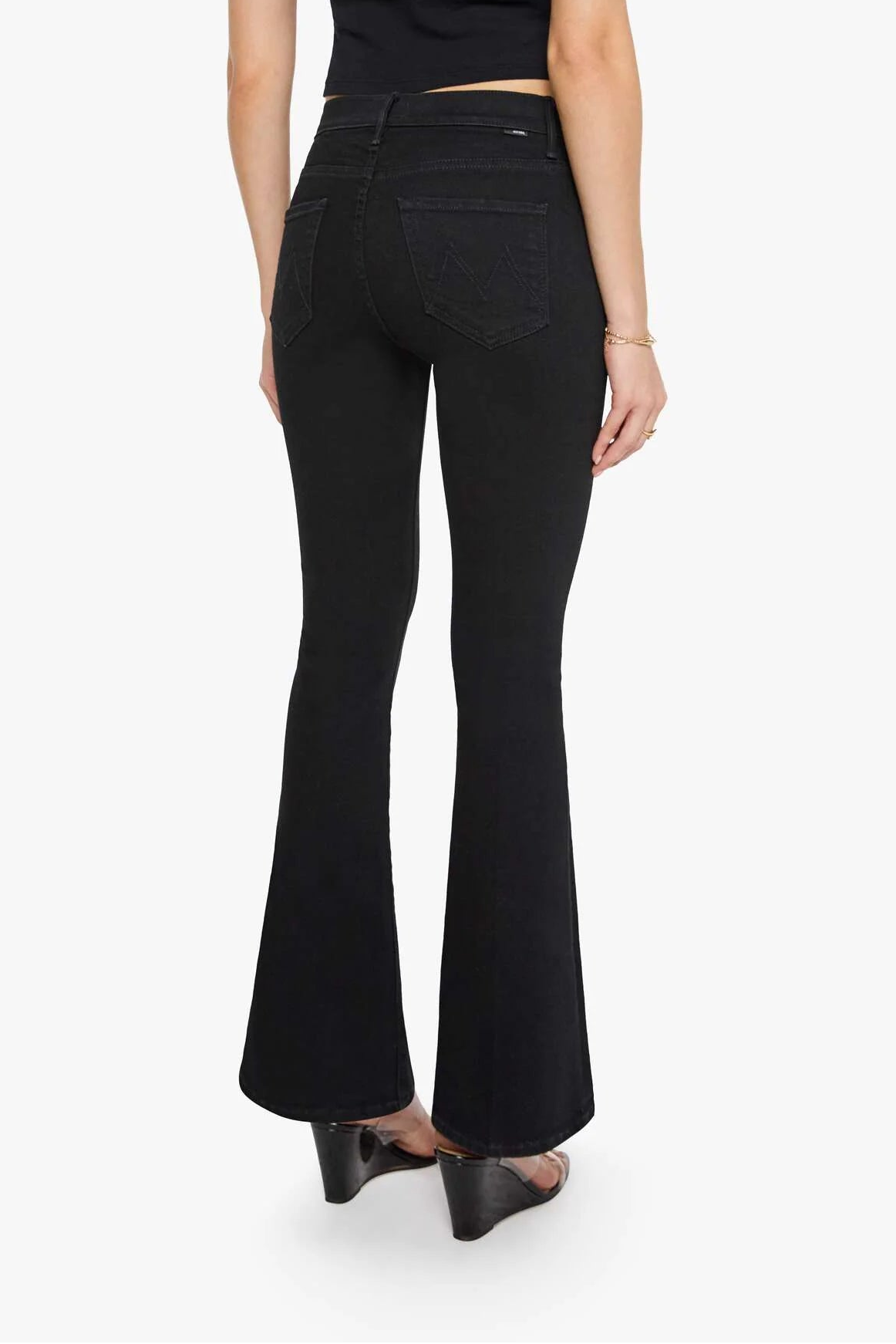 Woman wearing black flared jeans and a black top on a white background
