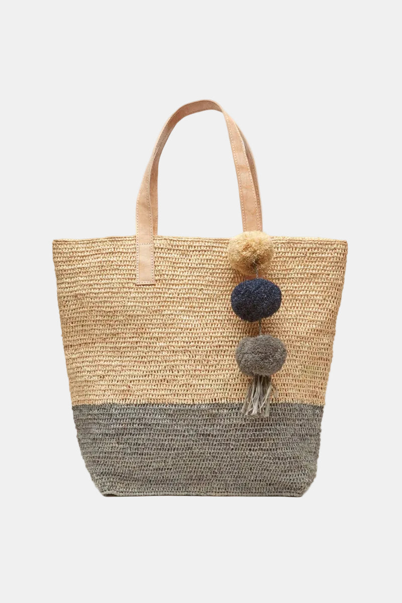 Woven tote bag with pom-pom details on a white background