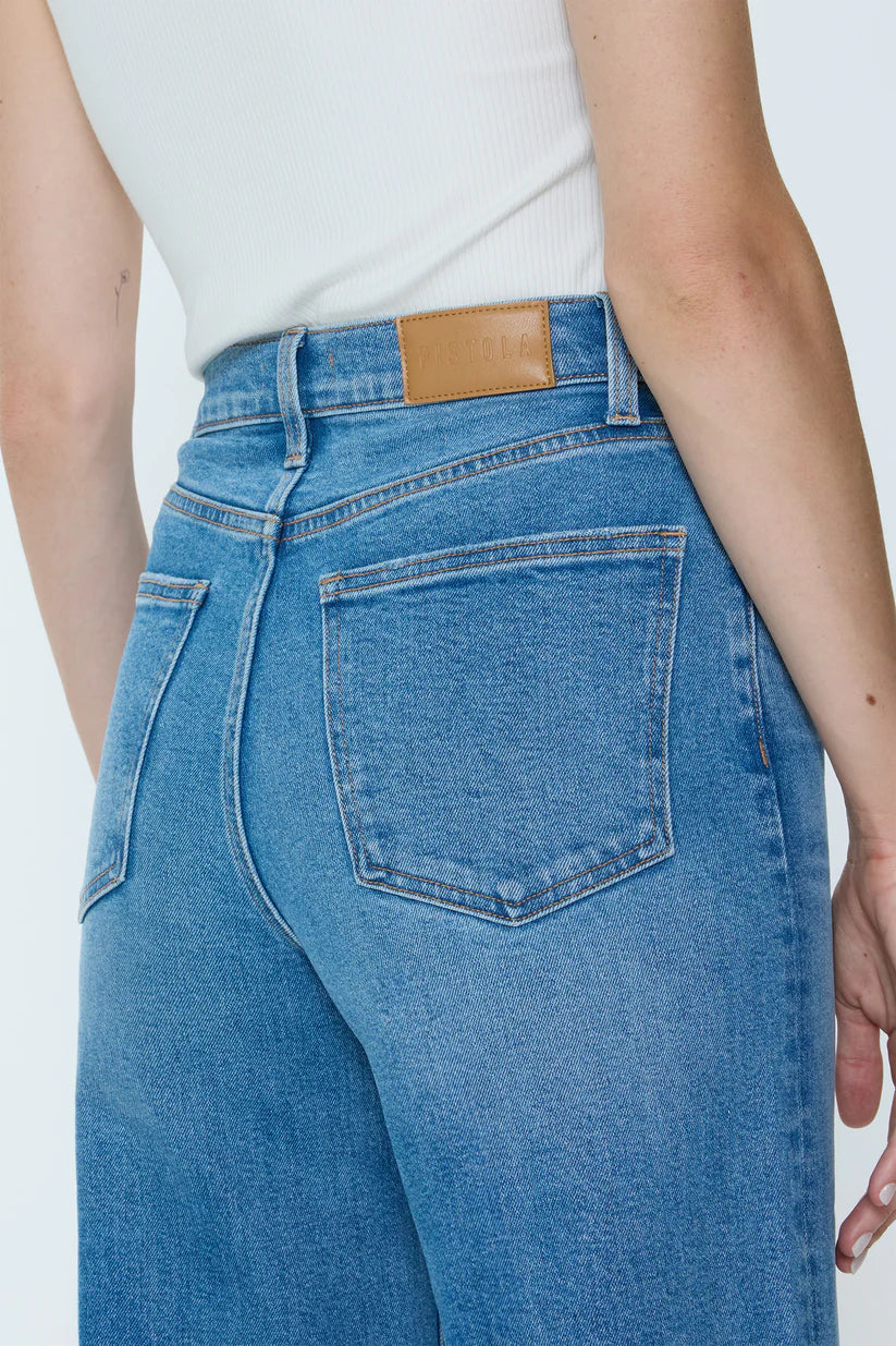 Blue jeans with a brown leather patch on a white background