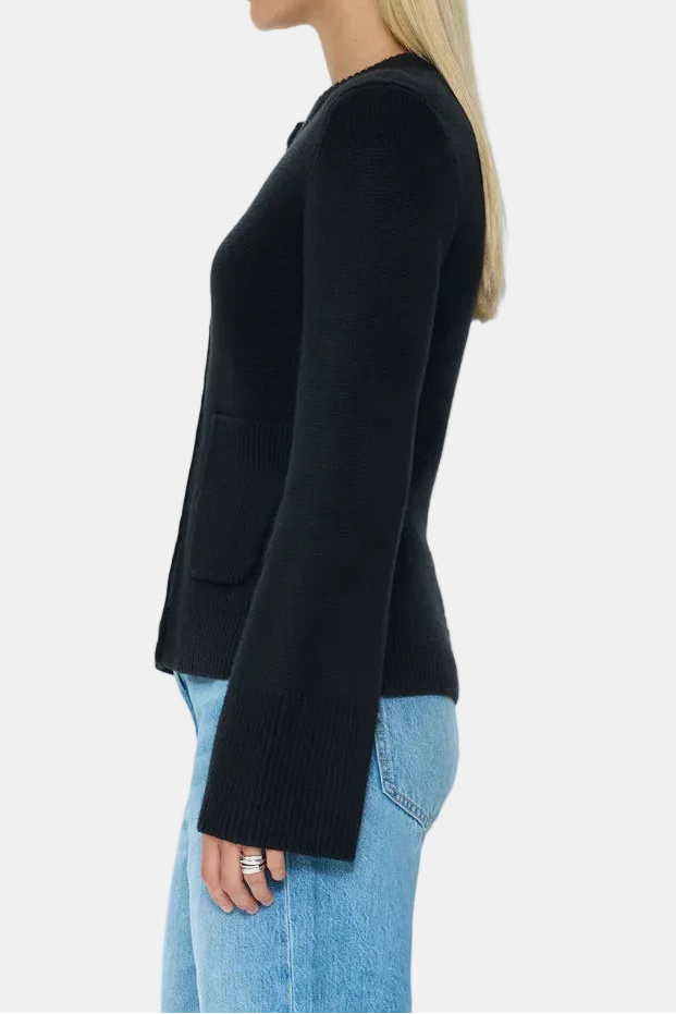 Woman wearing a black cardigan and blue jeans on a white background