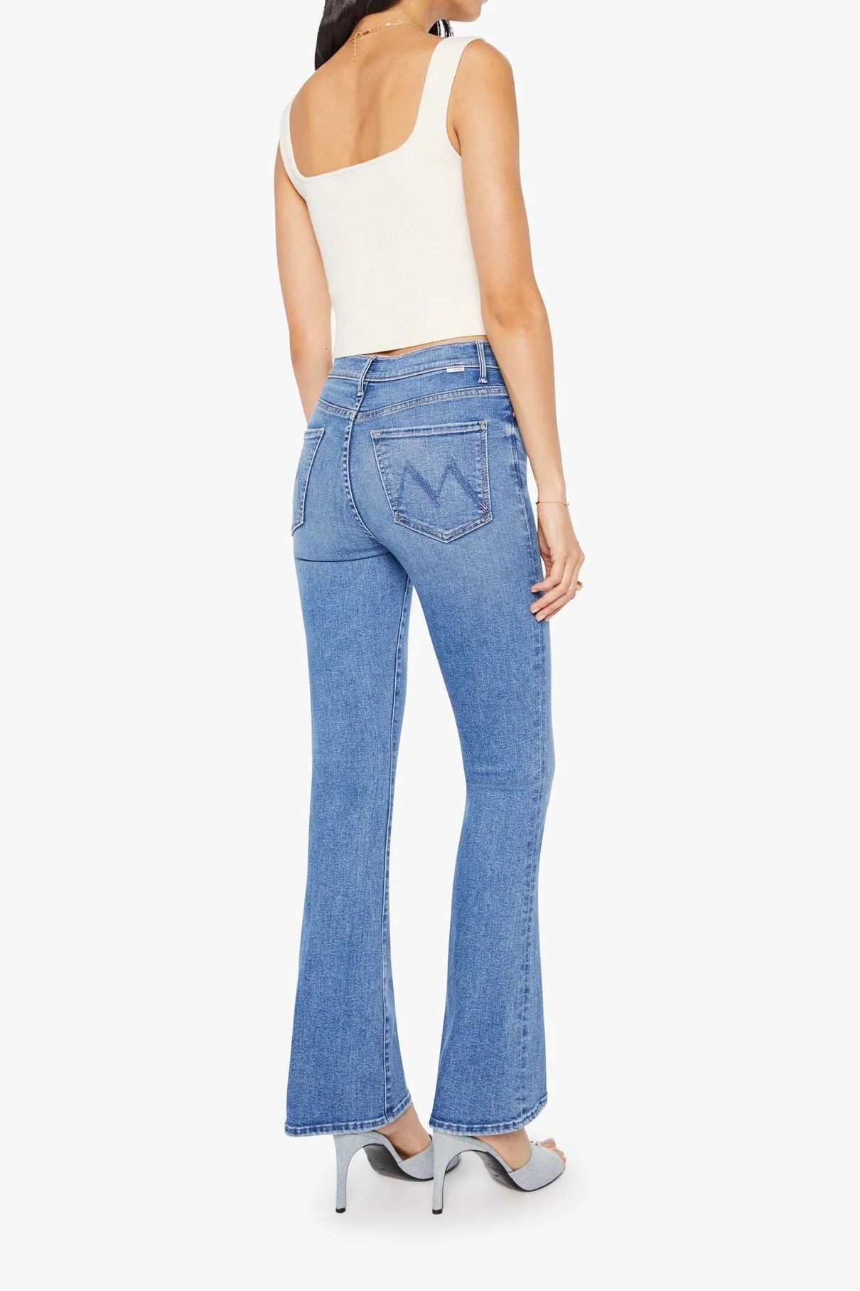 Woman wearing blue jeans and a white top on a white background