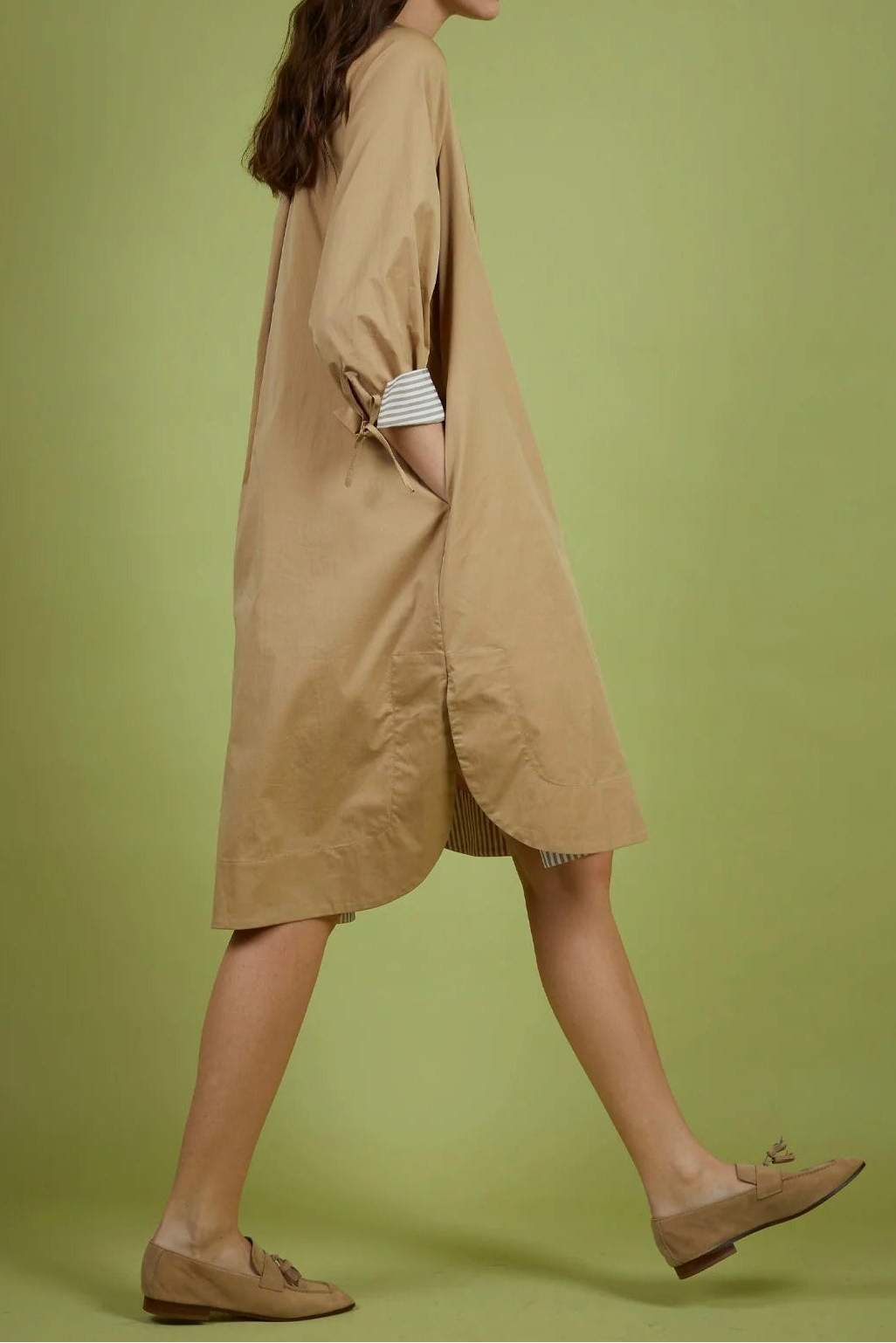 Woman wearing a beige dress against a green background