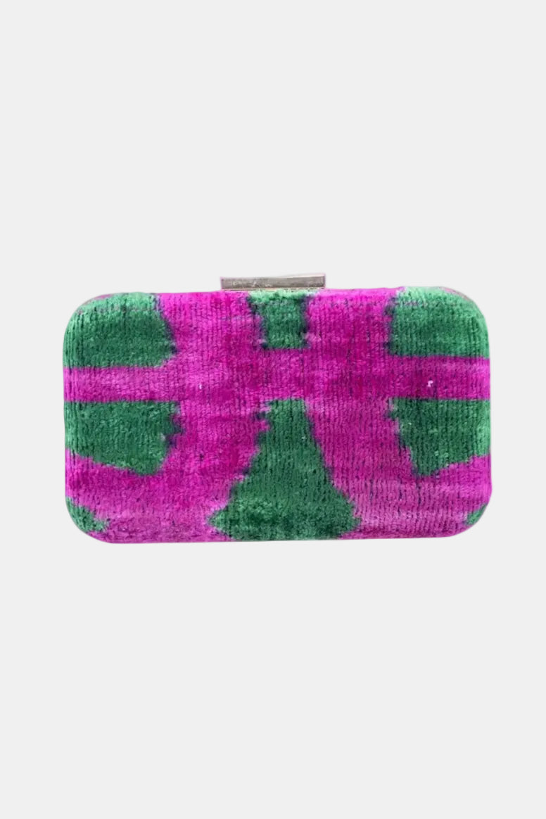 A rectangular clutch purse with rounded corners, featuring a textured fabric cover with a bold pink and green abstract pattern, and a silver metal clasp at the top, shown against a plain white background.