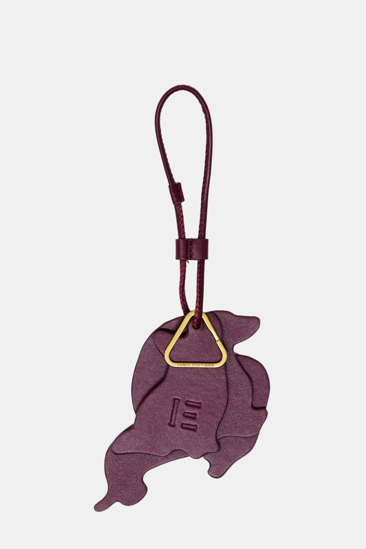 Dog-shaped keychain with a gold accent on a light purple background