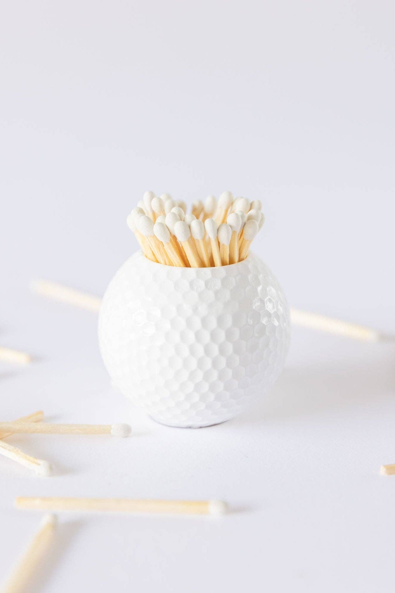 White textured container with wooden sticks on a light gray background