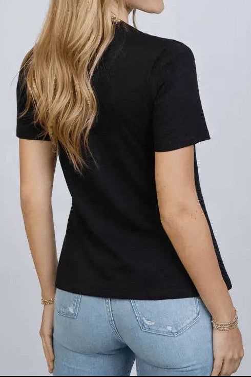 Woman wearing a black t-shirt and light blue jeans against a plain background