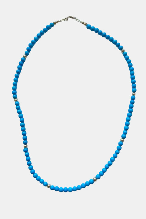 Blue beaded necklace on a marble surface