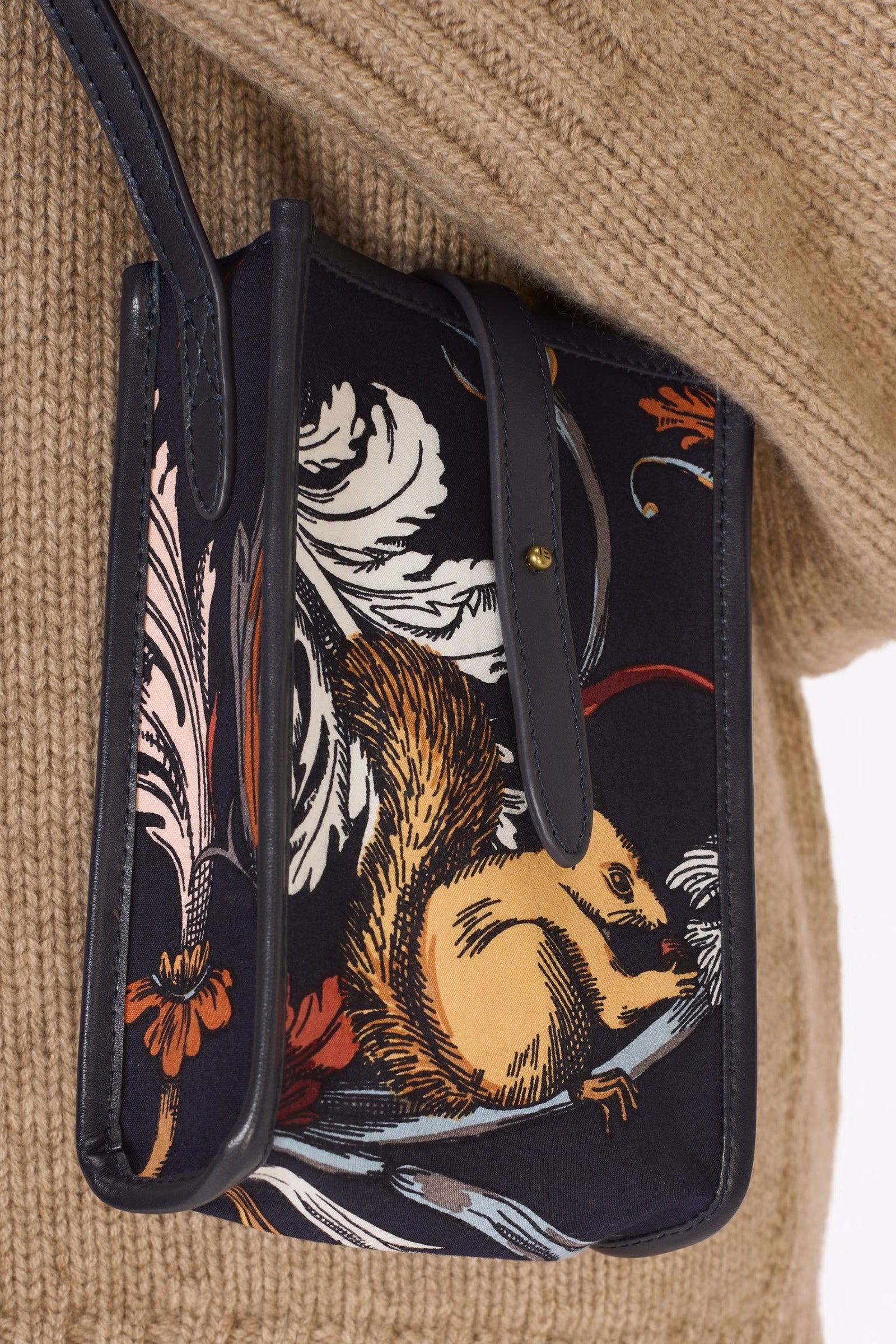 Small pouch with a squirrel design held by a person wearing a beige sweater.