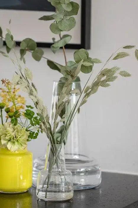 Two vases with flowers on a table against a plain wall.