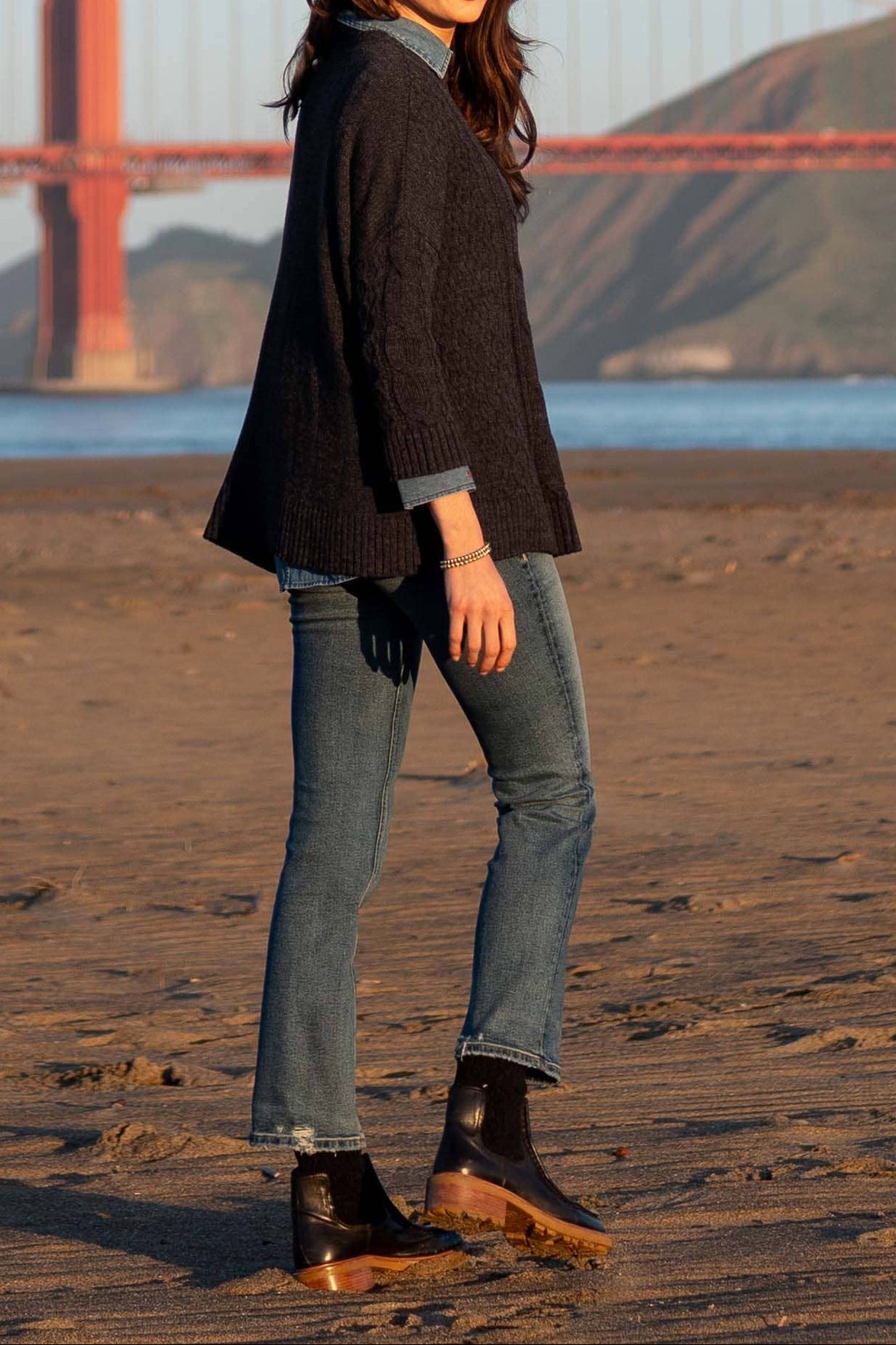 Woman standing on a beach with the Golden Gate Bridge in the background