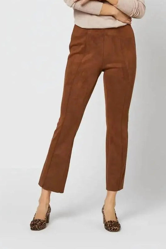 A model wearing brown cropped trousers and a beige turtleneck sweater, paired with leopard print flats, against a light gray studio background.
