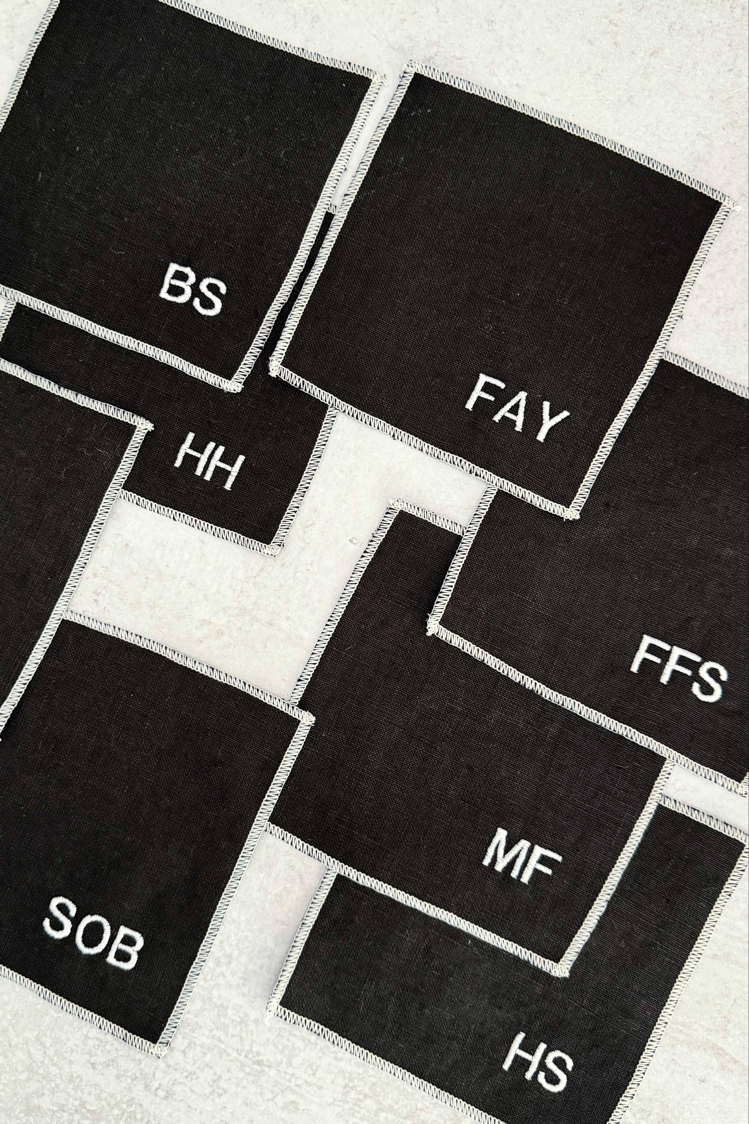 Black square coasters with white text on a textured surface