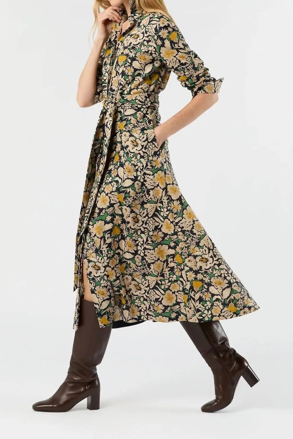 A woman models a knee-length floral print dress with a tie-neck and waist, paired with dark brown knee-high boots against a plain white studio background.