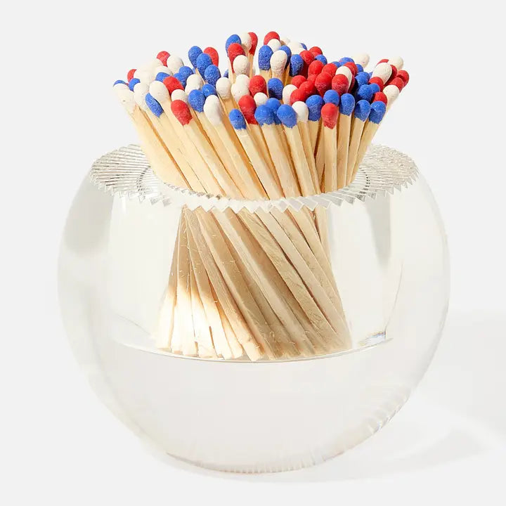 Clear glass match holder with red, white, and blue matches on a white background