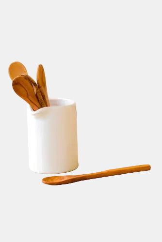 White ceramic container with wooden spoons on a wooden surface