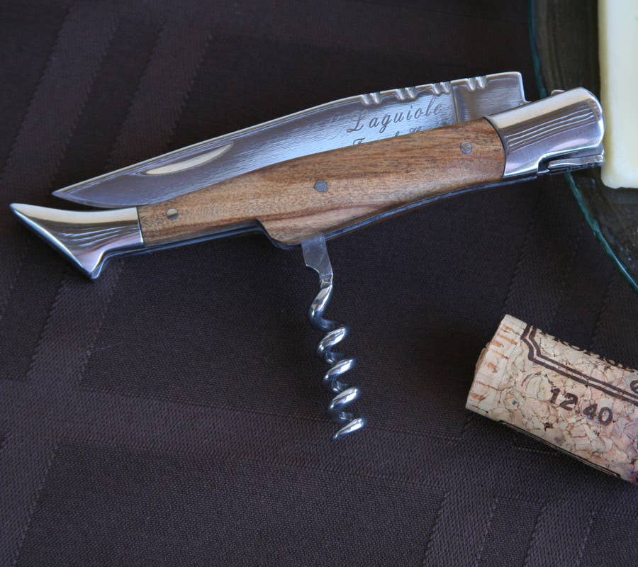 Wooden-handled corkscrew with Laguiole branding on a dark surface.