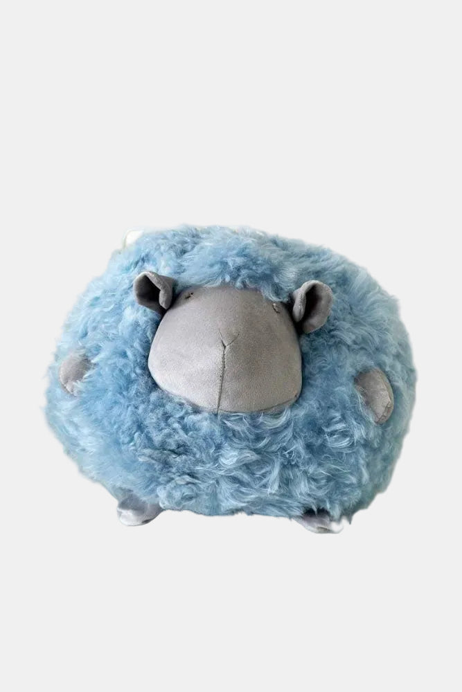 Blue plush sheep toy on a white surface with a neutral background