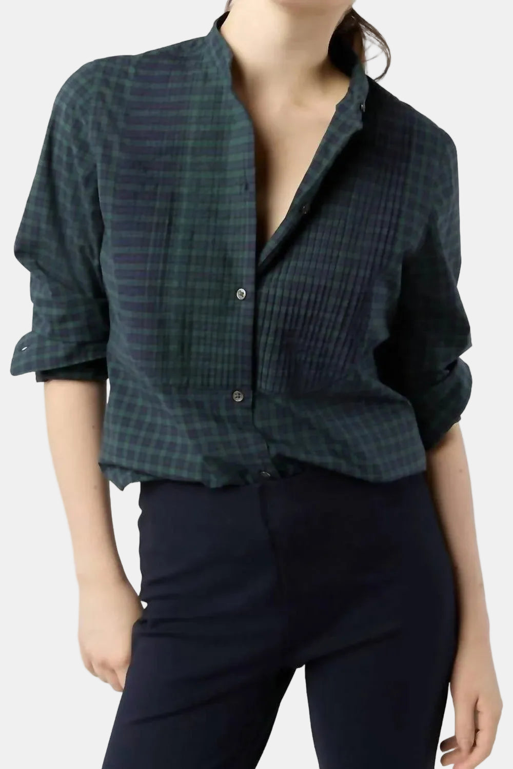 Person wearing a green plaid shirt and dark pants on a white background