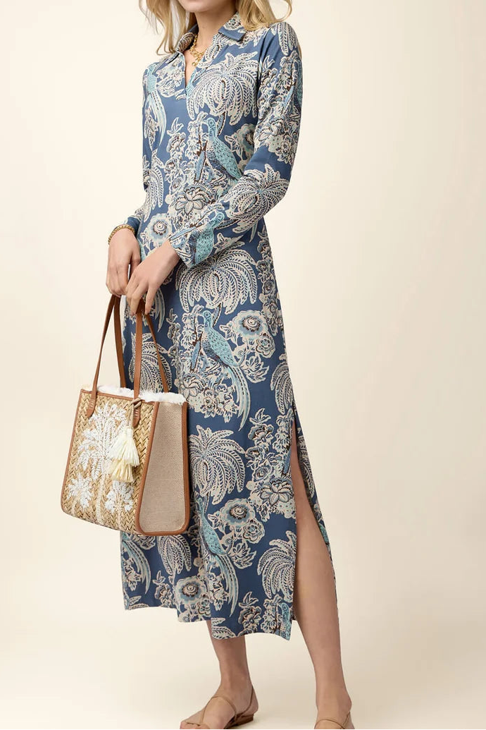Woman wearing a blue patterned dress holding a matching handbag on a beige background