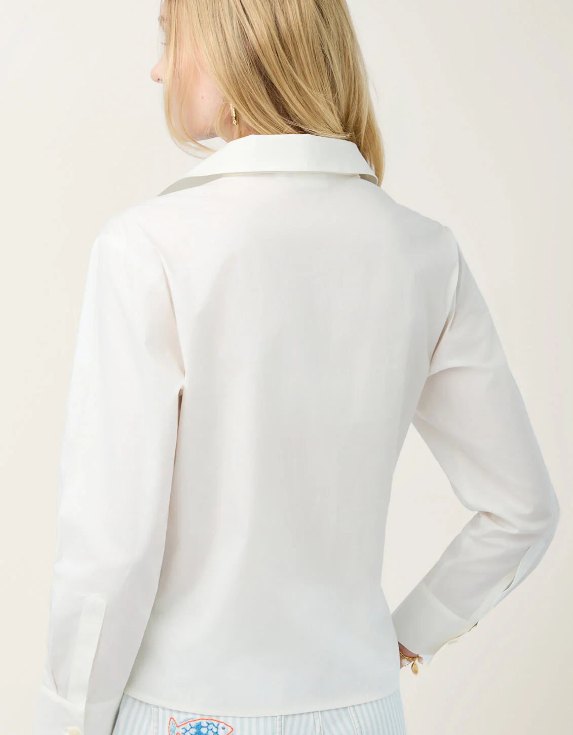 Woman wearing a white long-sleeve top against a light background