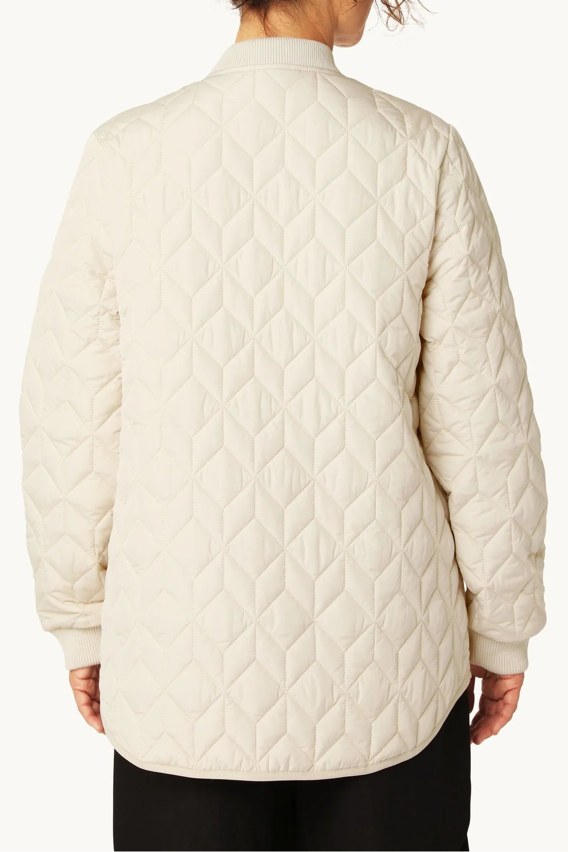 Person wearing a cream quilted jacket on a white background