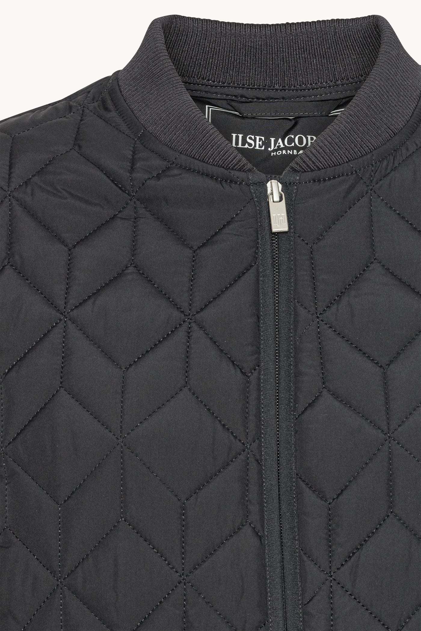 Close-up of a black quilted jacket with a brand label on a white background
