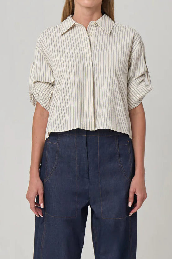 Woman wearing a striped shirt and dark pants on a plain background