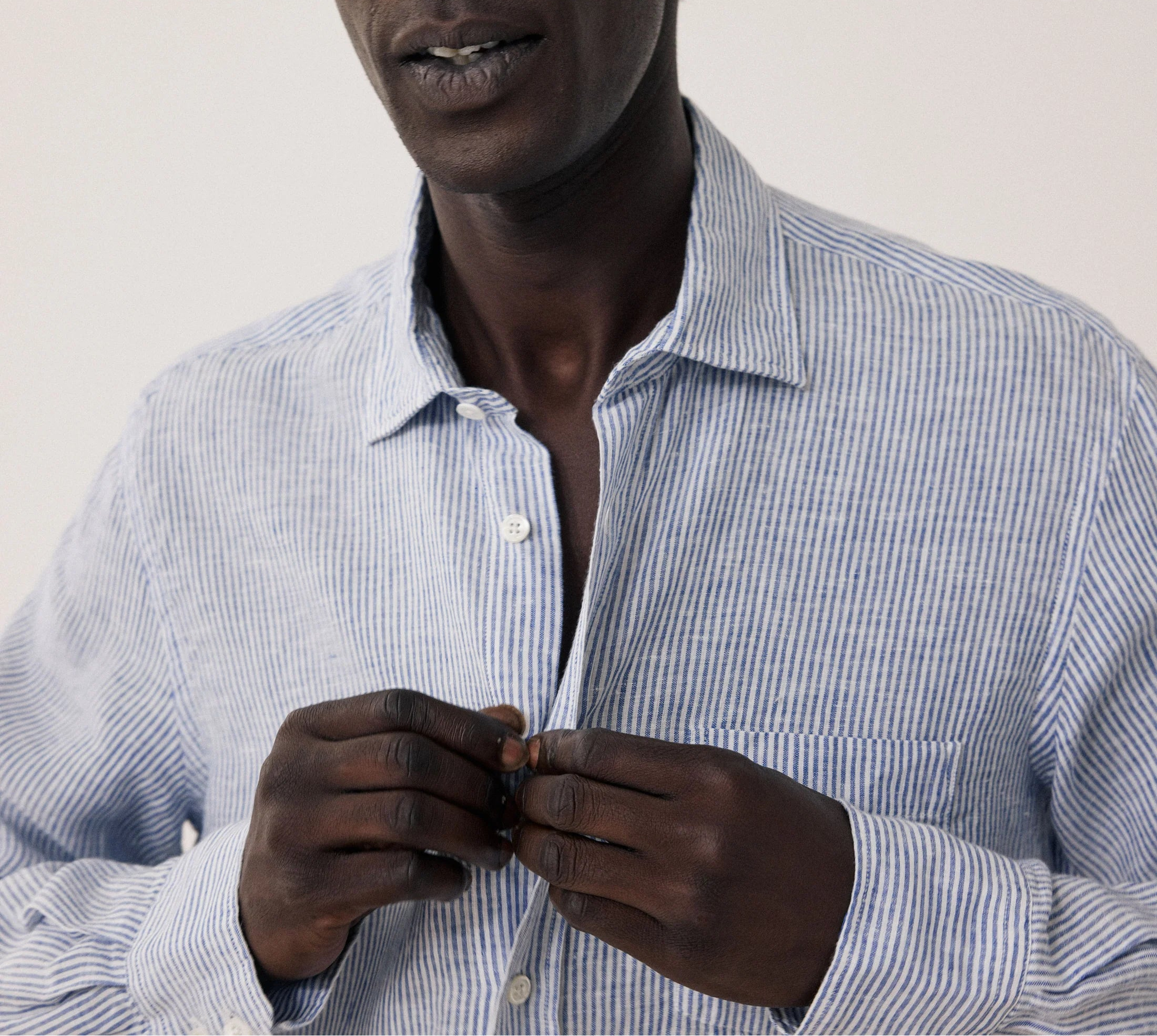 Man wearing a light blue striped shirt against a plain background