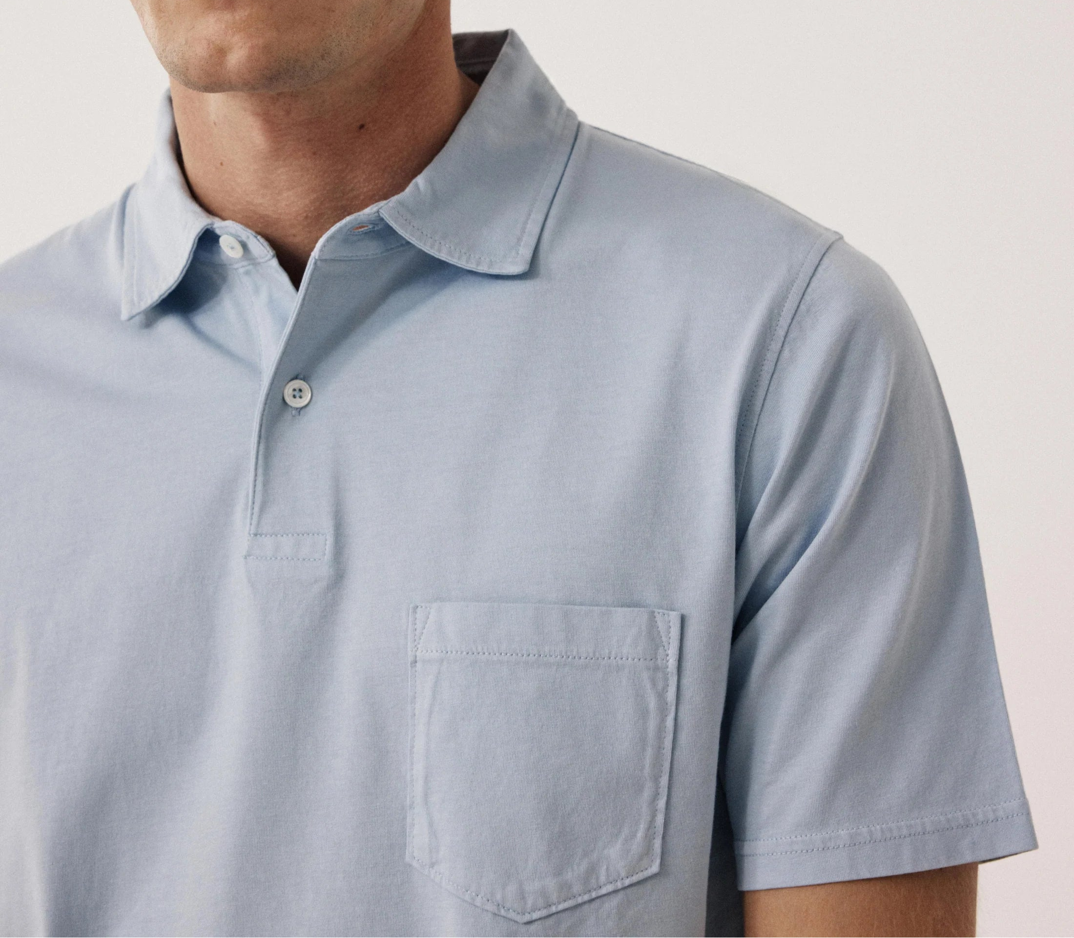 Man wearing a light blue polo shirt against a plain background